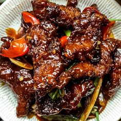 a white plate topped with meat covered in bbq sauce and vegtables