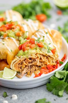 two burritos on a plate with guacamole and tomatoes