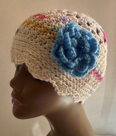 a crocheted hat with blue flower on top, sitting on a mannequin head