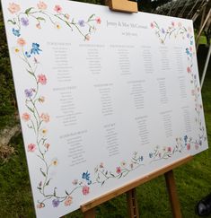 a white sign with flowers on it sitting in the grass