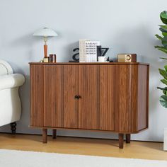 a wooden cabinet sitting next to a white couch and potted plant in a living room