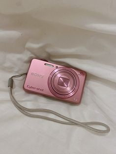 a pink camera sitting on top of a white sheet