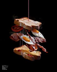 bacon, eggs, and toast hanging from strings in the air with hot sauce on them