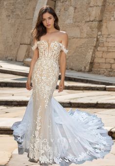 a woman in a wedding dress walking down the street with her hand on her hip