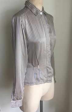 "Elegant fitted gold/blue/white silk charmeuse blouse with shell buttons and dolman sleeves has darting in the front and back, perfect for tucking it into your favorite high waist pants. Made by Michelle Stuart of 100% silk, labeled a size 10, but please do check the measurements, as a modern 10 is quite different from a vintage size 10. Shoulders 15-16\" Chest 40\" Waist 32\" Hem 40\" Arm Length from armpit to cuff 19.5\" Length from top of neck to hem 24.5\" Vintage garments have been previous Elegant Office Tops With Vertical Stripes, Elegant Vertical Stripe Office Tops, Formal Fitted Striped Tops, Blue Vertical Striped Tops For Formal Occasion, Chic Formal Blouse With Vertical Stripes, Formal Striped Fitted Tops, Blue Vertical Stripes Top For Formal Occasions, Fitted Vertical Stripes Office Tops, Elegant Office Blouse With Vertical Stripes