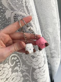 a person holding two keychains in their hands, one is pink and the other is white