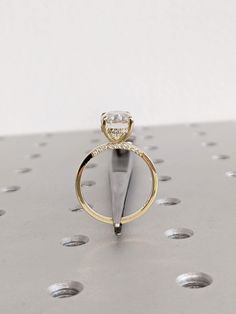 an engagement ring with a single diamond on top of it, resting on a piece of metal