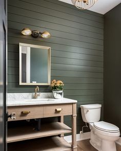 a white toilet sitting next to a sink in a bathroom under a chandelier