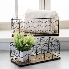 two metal baskets with plants in them on the floor next to a window sill