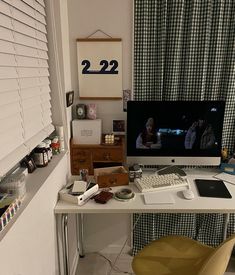 a computer desk with a monitor, keyboard and mouse on it in front of a window