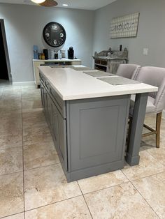 a kitchen island with two chairs and a clock on the wall