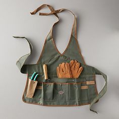 an apron with gardening tools hanging from it's back and two pairs of gloves in the pocket