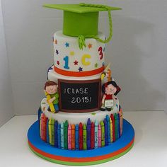 a three tiered cake decorated with children's graduation decorations