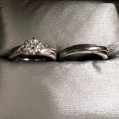 two wedding rings sitting next to each other on top of a silver cloth covered bed