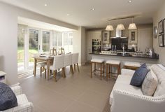 a living room filled with furniture next to a kitchen and dining room table in front of a window