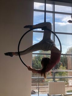 a woman is doing aerial tricks on a hoop