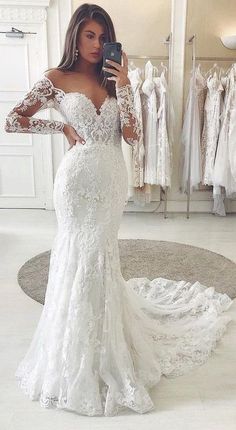 a woman taking a selfie in front of a mirror wearing a white wedding dress