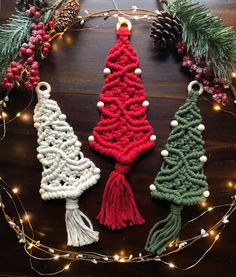 crocheted christmas tree ornaments are displayed on a table with pine cones and lights