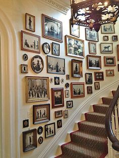 a staircase with many pictures on the wall and a chandelier hanging above it