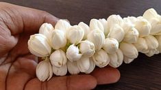 a hand holding white flowers on top of a wooden table