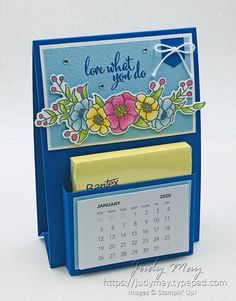 a blue desk calendar holder with flowers on it and a note pad attached to the front