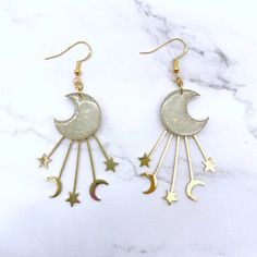 Channel the Celestial Glow with Golden Crescent Moon and Star EarringsEnchant any outfit with these magical moon earrings. Each earring features a delicate crescent moon charm adorned with stars, gracefully dangling from gleaming gold-colored hook wires.Details:Length: 2 inchesWidth: 1.5 inchesMaterial: Polymer clay, gold colored brass charms and findingsClosure: Secure pushback closureCrafted with lightweight polymer clay, these earrings measure approximately 2 inches long and 1.5 inches wide, Celestial Moon Shaped Earrings With Star Charm, Celestial Moon Earrings With Star Charm, Celestial Moon-shaped Earrings With Star Charm, Gold Moon Shaped Earrings For Party, Gold Moon-shaped Earrings For Party, Gold Moon-shaped Party Earrings, Celestial Crescent Earrings With Star Charm, Celestial Crescent Earrings For Party, Gold Half Moon Celestial Earrings