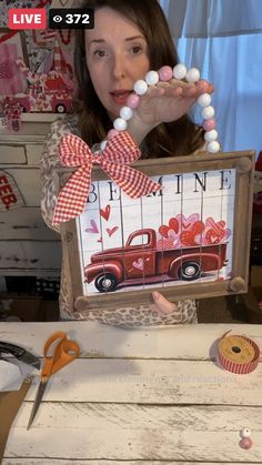 a woman is holding up a sign with an image of a truck and hearts on it