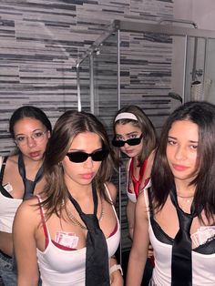 four women wearing blindfolds are posing for a photo in front of a mirror