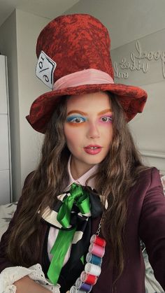 a woman with long hair wearing a red hat and green ribbon around her neck is posing for the camera