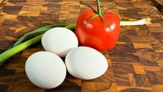 three eggs and a tomato on a cutting board