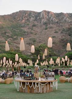 an outdoor event with tables and chairs set up in front of a mountain side backdrop