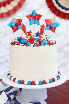 a white cake with red, white and blue decorations on it sitting on a table