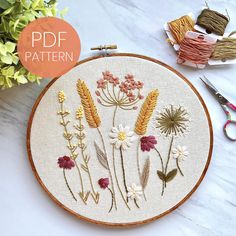 an embroidery pattern with flowers on it and scissors next to the sewing needle, along with other items