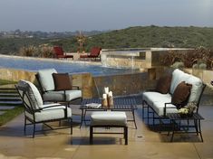 an outdoor living area with chairs, tables and a pool in the backgroud