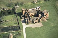 an aerial view of a large brick building in the middle of a green field with lots of trees