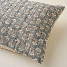 a blue and white pillow sitting on top of a bed