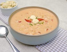 there is a bowl of soup on the table next to a spoon and some crackers