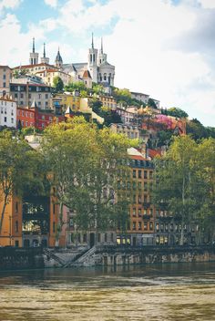 a city with lots of tall buildings on top of it's hill next to the water