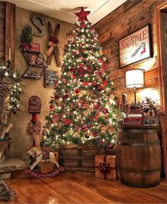 a decorated christmas tree in the corner of a room with wooden walls and wood floors