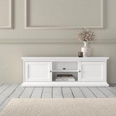 a white entertainment center with a vase on top