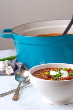 a white bowl filled with soup next to a blue pot