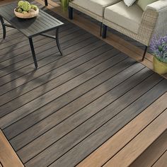 a wooden deck with two chairs and a table next to it on top of the floor