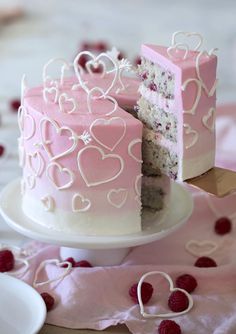 a pink cake with white frosting and hearts cut in to it's sides