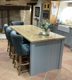 a large kitchen island with blue chairs in front of it and a fireplace behind it