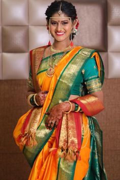 a woman in a yellow and green sari with gold accents on her face, smiling