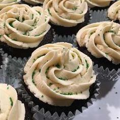 cupcakes with white frosting and green sprinkles are on a tray