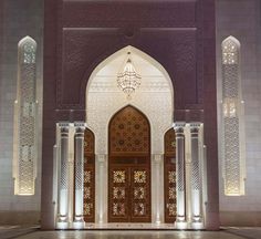 the entrance to an ornate building lit up at night with lights on and chandeliers hanging from the ceiling