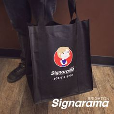 a black shopping bag with a woman's face on it and the signama logo