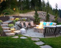 an outdoor fire pit surrounded by stone steps and lawn furniture with lights on the side