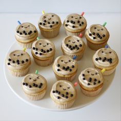 there are many cupcakes with candles in the shape of smiley faces on this plate